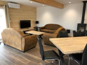 a living room with couches and tables and a television at Chalet Jersey in Gérardmer
