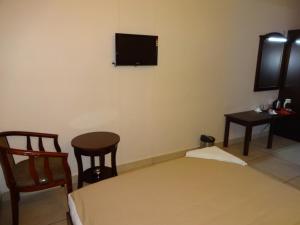 a room with a bed and a tv on the wall at Hotel Sky Lite in Coimbatore