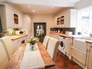 a kitchen with a table with chairs and a sink at Buttercross Cottage in Rugeley