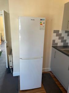 a white refrigerator freezer sitting in a kitchen at Vibrant & Cosy London Apartment Near Wembley in London