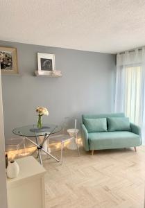 ein Wohnzimmer mit einem blauen Sofa und einem Glastisch in der Unterkunft Lovely Appartment Cannes Marina in Mandelieu-la-Napoule