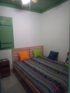 una cama con almohadas coloridas en una habitación en Baranca Stima en Aldeia de Além