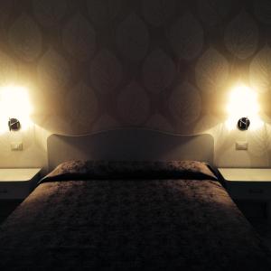 a bedroom with a bed and two lights on the wall at Le Camere del Vascello d'Oro in Carrù