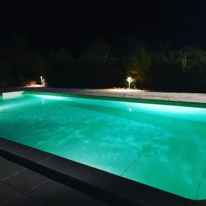 una piscina iluminada por la noche en Chbre Tamara du Château avec Piscine en Pépieux