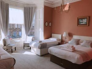 una camera con due letti e una sedia e una finestra di Alexander Guest House a Edimburgo