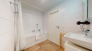 a white bathroom with a tub and a sink at Nice apartments at 10min from Payerne, fully equipped in Vers chez Perrin