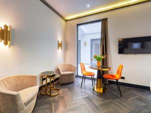 Habitación con sillas, mesa y TV. en Triple G Hotels, en Ámsterdam