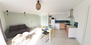 een woonkamer en een keuken met een bank en een tafel bij LA PIERRINA - Marmotte - Appart 3 étoiles in Aix-les-Bains