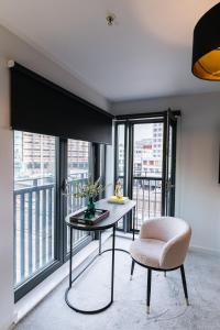 a room with a table and a chair and windows at The Lusso Suite - 2BR - A 5* Escape Like No Other in Glasgow