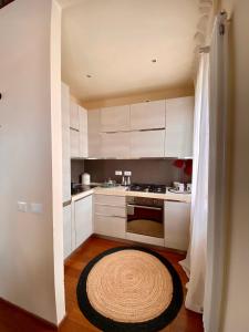 una cocina con armarios blancos y una alfombra en el suelo en DUOMO Murano Apartment with Canal view en Murano