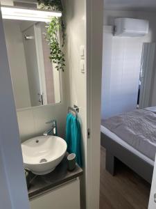 a bathroom with a sink and a bed and a mirror at Mobile Home Jana in Biograd na Moru