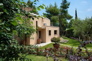 ein Haus in einem Garten mit einem Zaun in der Unterkunft Anemone Villa, Sani Luxury Villas collection in Sani Beach