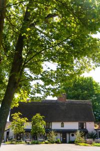 uma grande casa branca com telhado de palha em The Black Bull Inn em Balsham