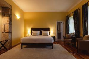 a bedroom with a bed and a couch and a chair at Glicínia Boutique Hotel in Freamunde