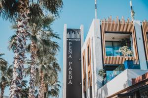 a sign on the side of a building with palm trees at H Boutique Peña Parda in La Herradura