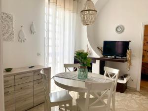 uma sala de jantar branca com uma mesa e uma televisão em Litosoru Casa Vacanze em Savelletri di Fasano