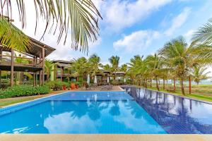 uma piscina em frente a um resort com palmeiras em IT12 Lindo Bangalô Duplex 2 Suítes Pé na Areia, Itacimirim em Itacimirim