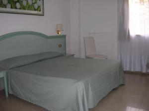 Un dormitorio con una cama verde y una silla en Chiara Stella, en Roma