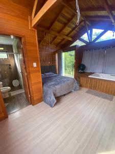 a bedroom with a bed and a tub in a room at Chalé Guest House in Urubici