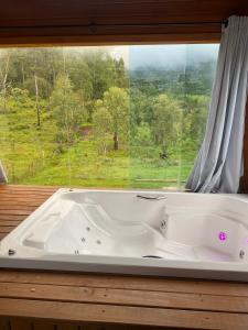 a bath tub in a room with a window at Chalé Guest House in Urubici