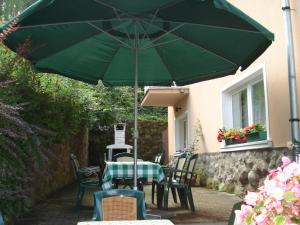 - une table avec un parasol vert sur la terrasse dans l'établissement Vila Intim, à Sovata