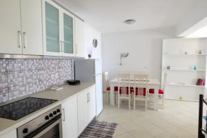 a kitchen with white cabinets and a dining room with a table at Duka's House in Lukovë