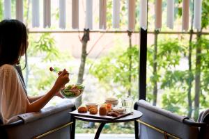 Una donna seduta a un tavolo con una ciotola di cibo di Tassel Hotel Sanjo Shirakawa a Kyoto