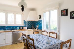 eine Küche mit einem Tisch und einer blau gefliesten Wand in der Unterkunft Jolie maison pour 8 personnes in Plobannalec-Lesconil