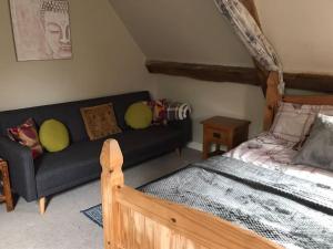 a living room with a couch and a bed at Woodmill Farm Cottage in Alvington