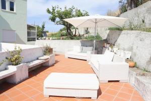 eine Terrasse mit weißen Stühlen und einem Sonnenschirm in der Unterkunft Casal de São José - Modern Country House in Mafra