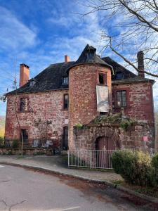 un vecchio edificio di mattoni con un cancello di fronte di Maison Dada et SPA a Meyssac