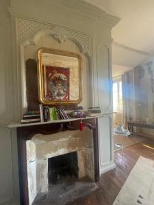 una chimenea en la sala de estar con un espejo encima en Maison Dada et SPA, en Meyssac