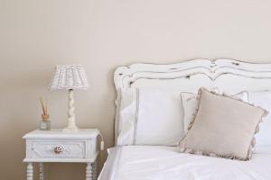 a bedroom with a white bed with a lamp and a nightstand at Casal de São José - Modern Country House in Mafra