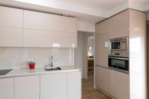 a white kitchen with a sink and a microwave at Casa Alvar - Califa Casas Vejer in Vejer de la Frontera +6 photos