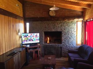 a living room with a fireplace and a tv at Cabaña Fer in Los Cipreses