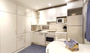 a white kitchen with white cabinets and a table at Corazón Cangues VUT2306AS in Cangas de Onís