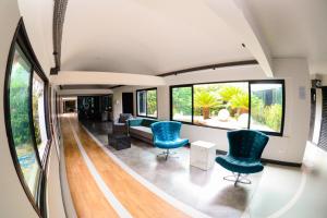 a living room with two blue chairs and windows at ibis Styles Rio Preto Monte Libano in Sao Jose do Rio Preto