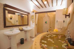a bathroom with a tub and a sink and a shower at Zanzibar Beach Resort in Zanzibar City