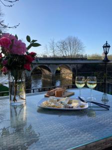 einen Tisch mit einem Teller Essen und zwei Gläsern Wein in der Unterkunft Le Moulin De Bretigneul in Saint-Aubin-des-Landes