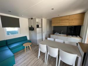eine Küche mit einem blauen Sofa, einem Tisch und Stühlen in der Unterkunft Camping LES PEUPLIERS in Hyères