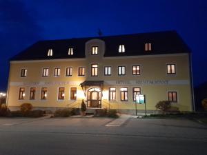 ein großes weißes Gebäude mit nachts eingeschaltetem Licht in der Unterkunft Hotel-Restaurant Kreuzhuber in Neuburg am Inn