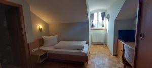 a small bedroom with a bed and a television at Hotel-Restaurant Kreuzhuber in Neuburg am Inn