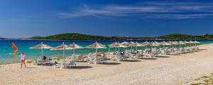 希貝尼克的住宿－VILLA MIRAKUL，海滩上的一组椅子和遮阳伞