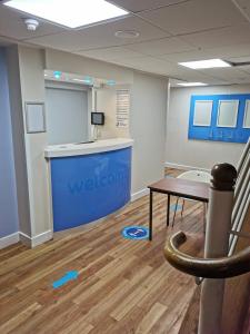 een wachtkamer met een tafel en een blauwe muur bij Thurrock Hotel M25 Services in Aveley