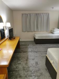 a room with two beds and a desk and a television at Thurrock Hotel M25 Services in Aveley