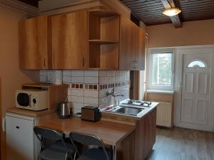 uma cozinha com armários de madeira, um lavatório e um micro-ondas em Egniss Apartman 2 em Bogács