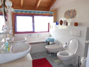 a bathroom with two sinks and a toilet and a tub at Blaues Haus - Une maison bleue in Hetzerath