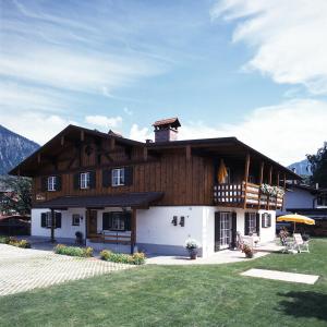 ein großes Holzhaus mit Rasen davor in der Unterkunft Landhaus Marie-Theres in Oberstdorf
