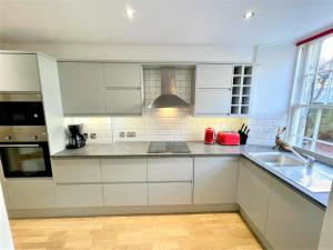 uma cozinha com armários brancos e um lavatório em Elite 3 Bed New Town Apt with Private Walled Garden em Edimburgo