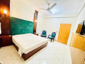 a bedroom with a bed and two blue chairs at Hotel New Mid City in Multan